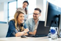 Drei Personen sitzen vor einem Computer und unterhalten sich über das Thema Management-Buy-In