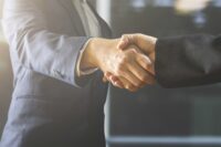 Zwei Menschen schütteln sich die Hände als Symbol für einen Unternehmensverkauf